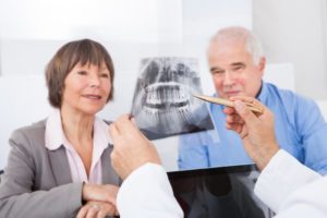 Dentist showing xray of teeth to elderly couple
